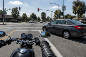Motorcycle approaching an intersection while a car waits or begins turning left